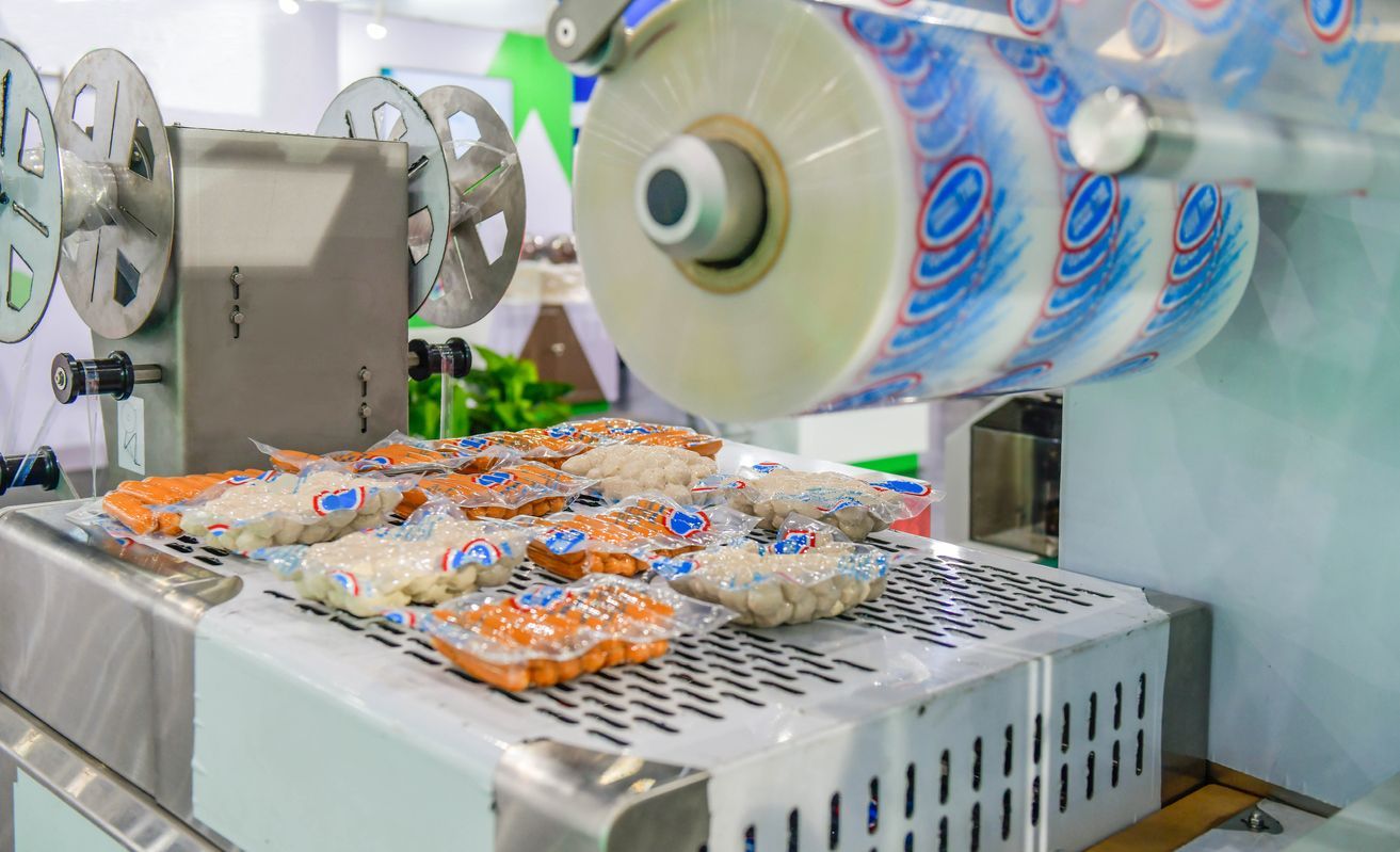 Overhead view of an industrial complex with buildings, tanks, parking, and green areas.