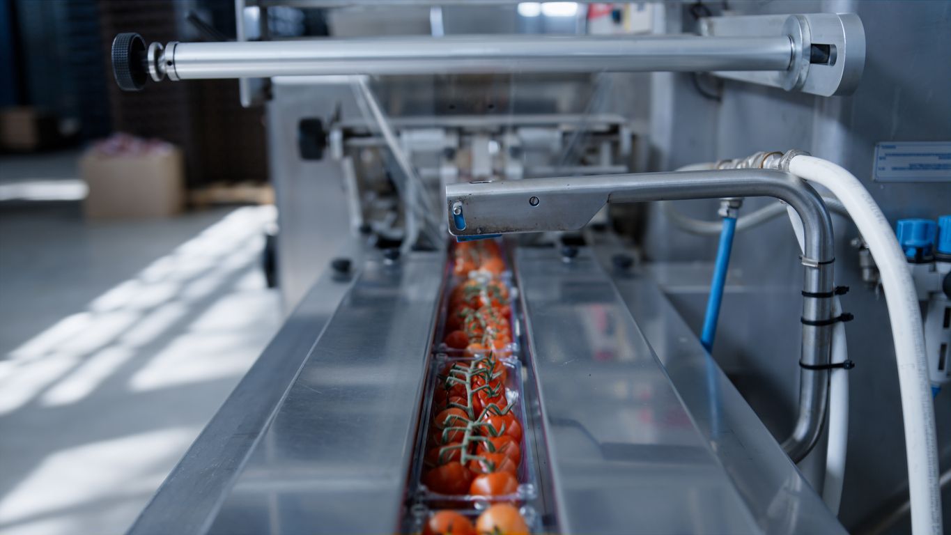 Bottling machine in a factory setting, filling glass bottles with liquid.