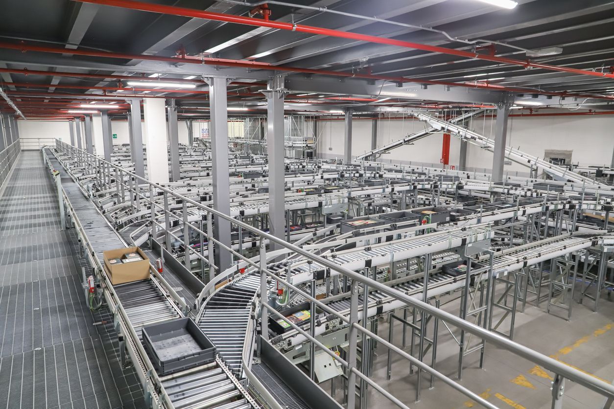 An industrial processing room featuring a large stainless steel tank, complex metal piping, and clean, sterile flooring.