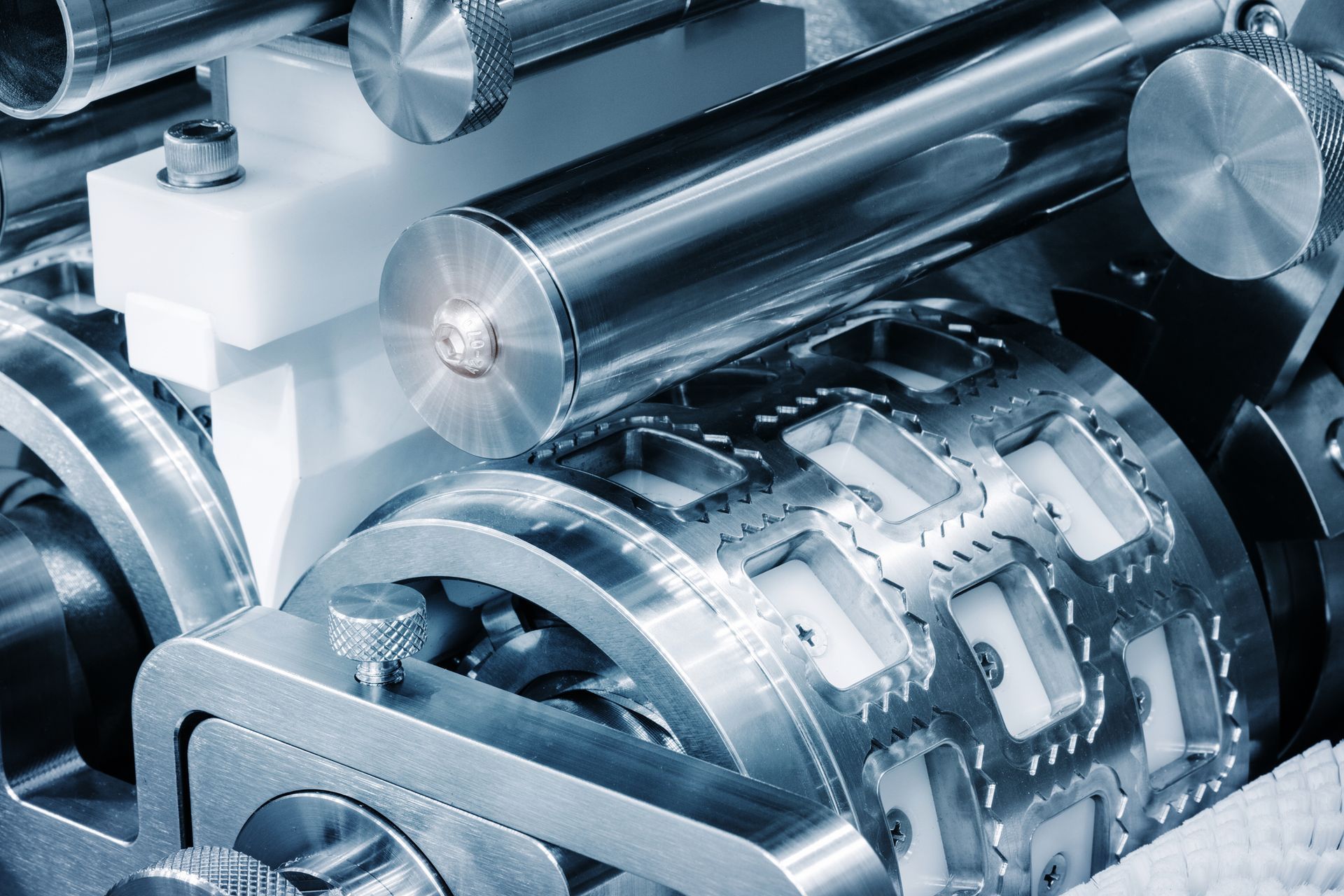 Close-up of metallic industrial machinery with multiple cylinders and complex gears.