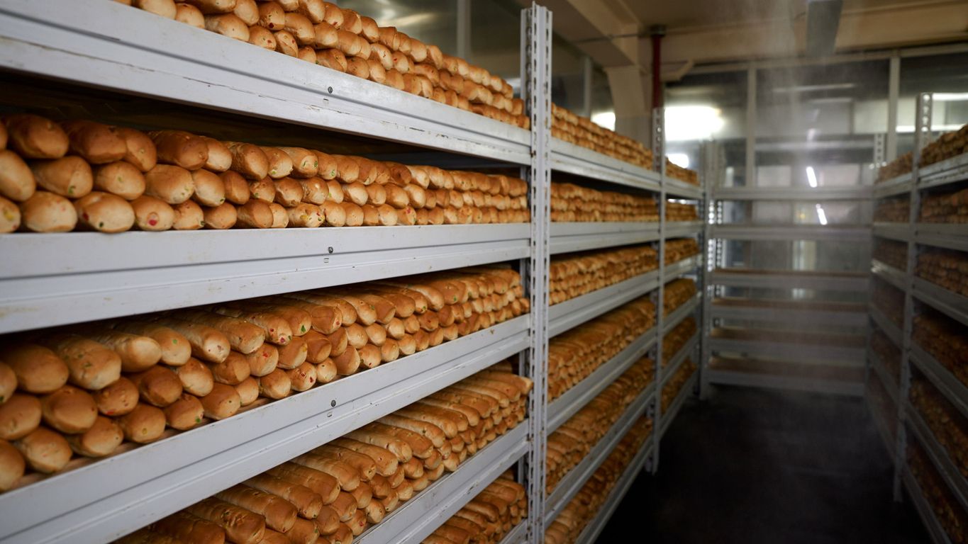 Bottling machine in a factory setting, filling glass bottles with liquid.