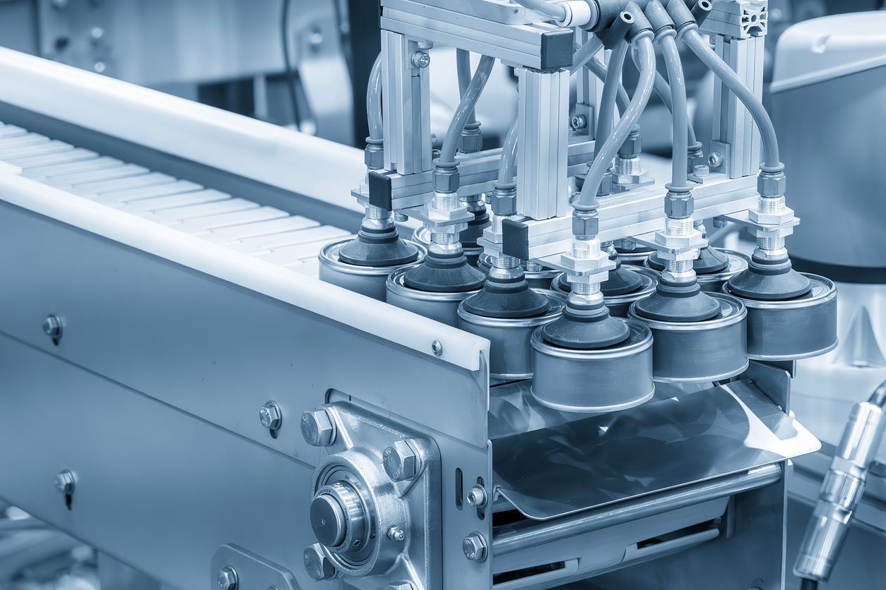 A multi-nozzle industrial filling machine processing items on a metallic conveyor belt.