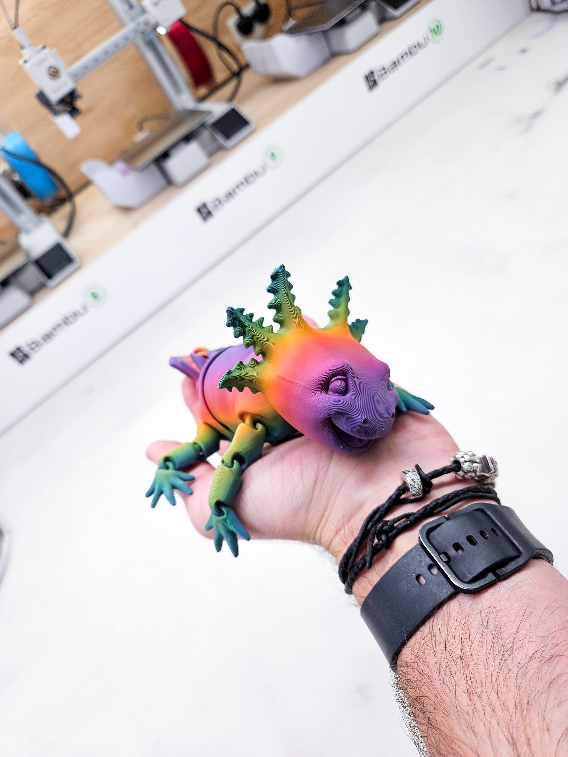 A colorful toy lizard is laying down on a white surface.