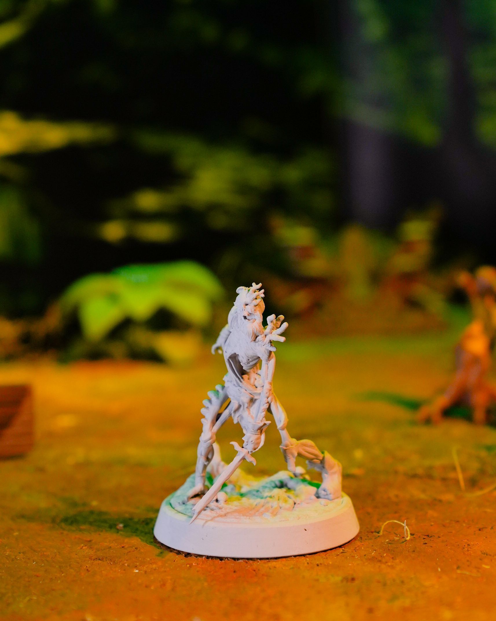 A statue of a skeleton holding a stick on a white base.