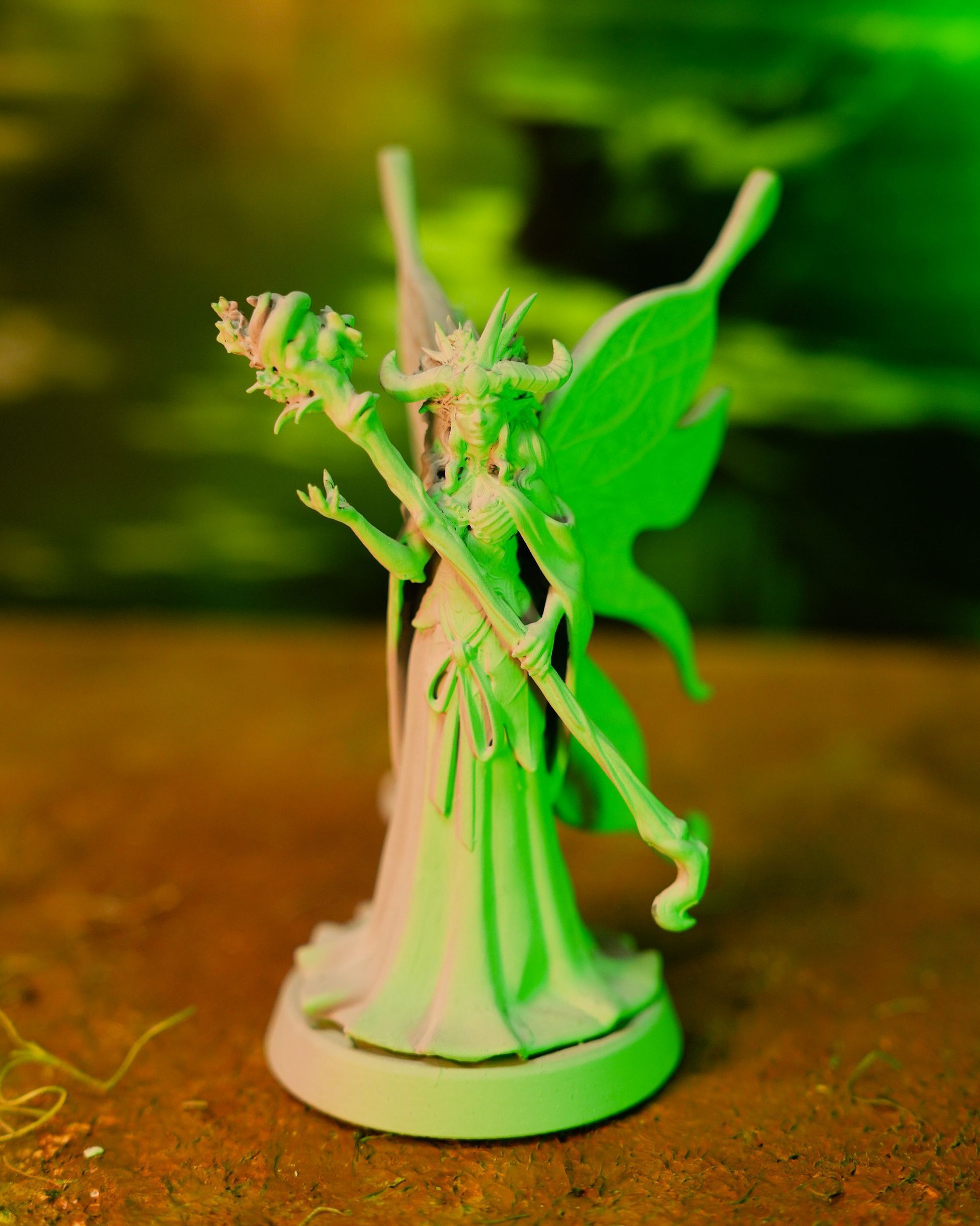 A statue of a fairy with green wings holding a wand