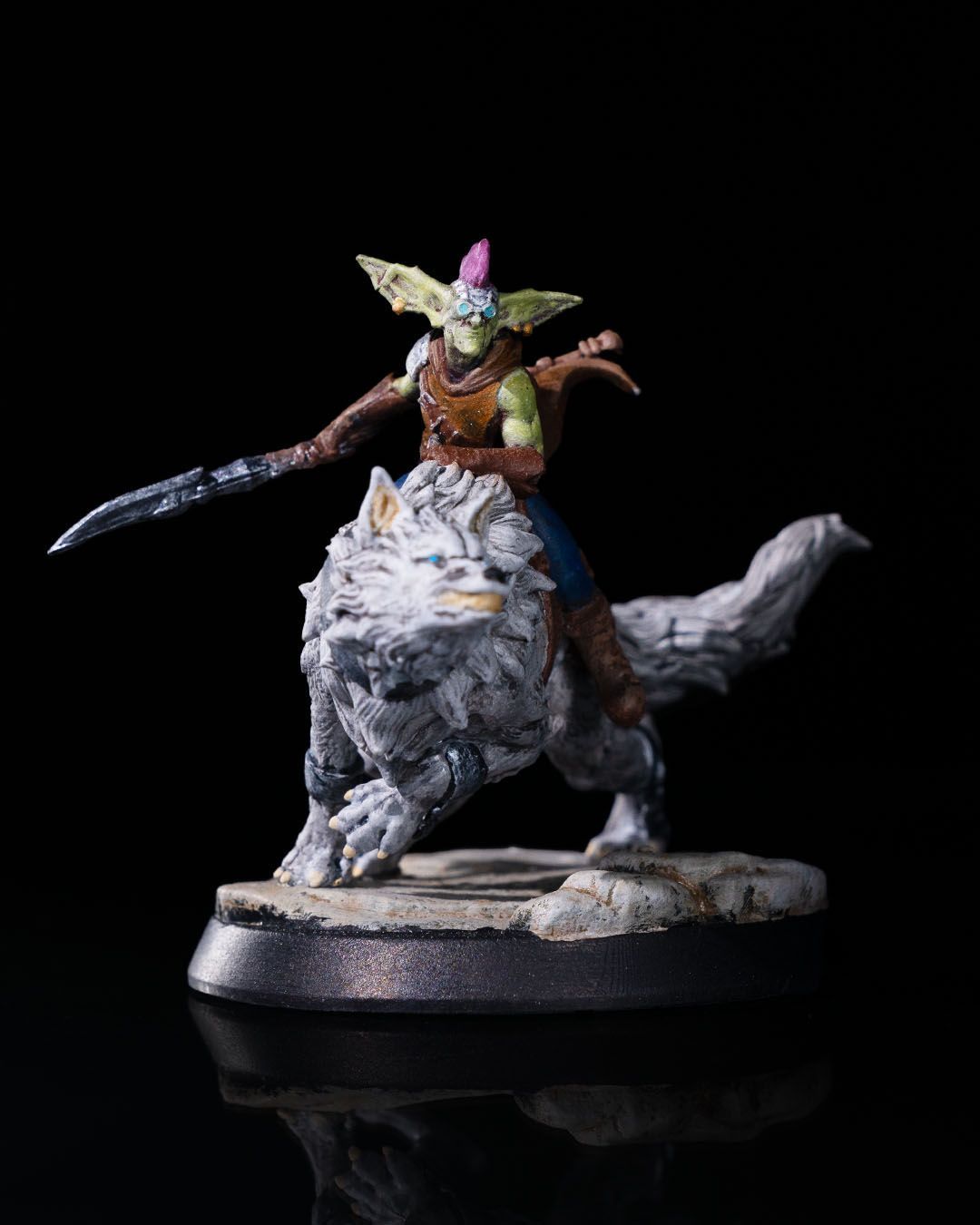 A figurine of a goblin riding on the back of a wolf.