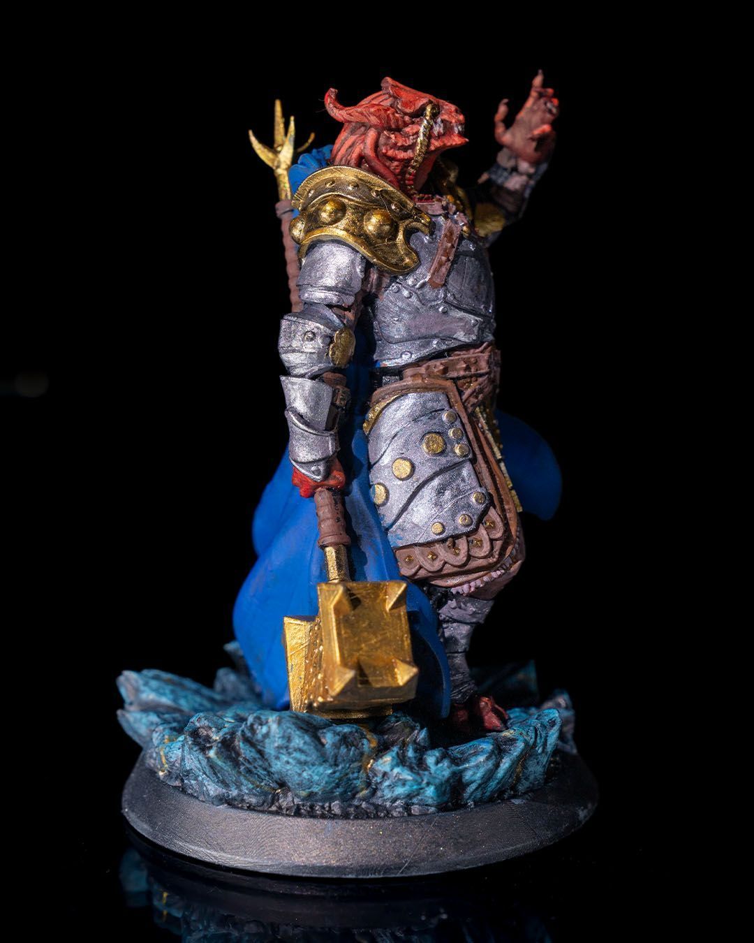 A statue of a knight with a blue cape and a hammer.