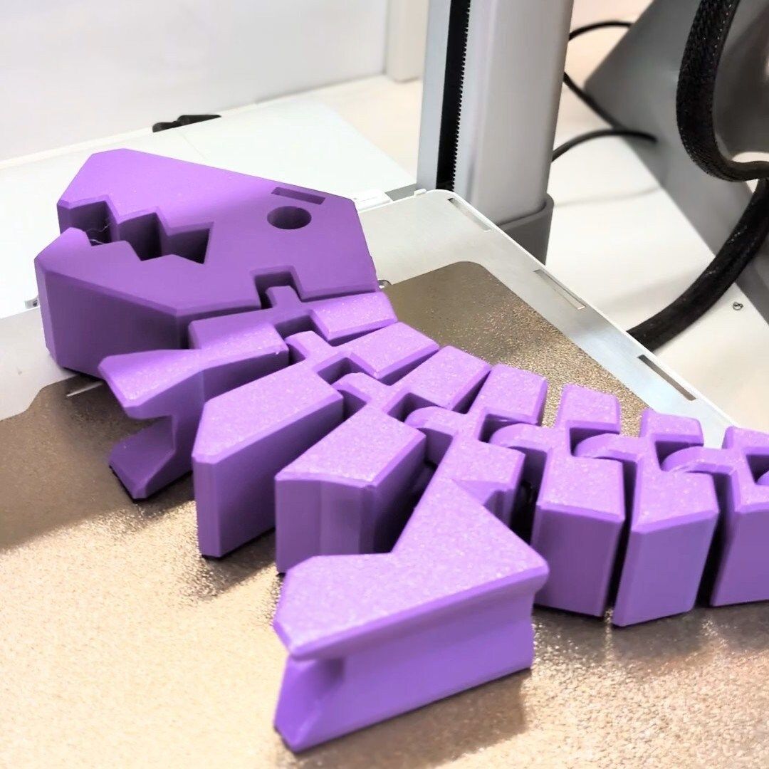 A close up of a pink dinosaur toy on a white background.