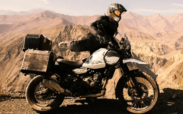 Adventure motorcyclist riding a white bike on a rocky desert trail with mountains in the background