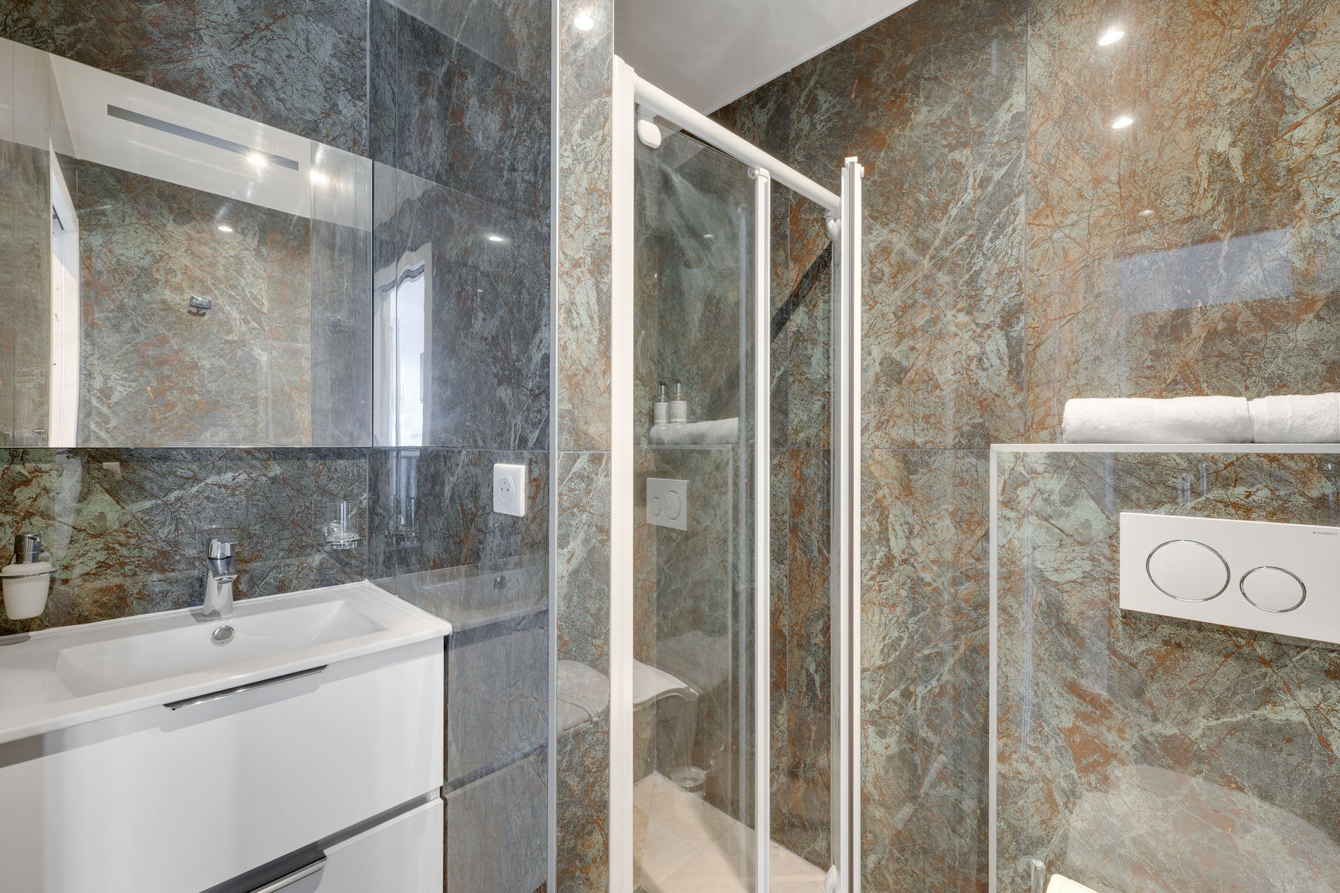 Modern bathroom with stone tile walls, a glass shower, and a white vanity.