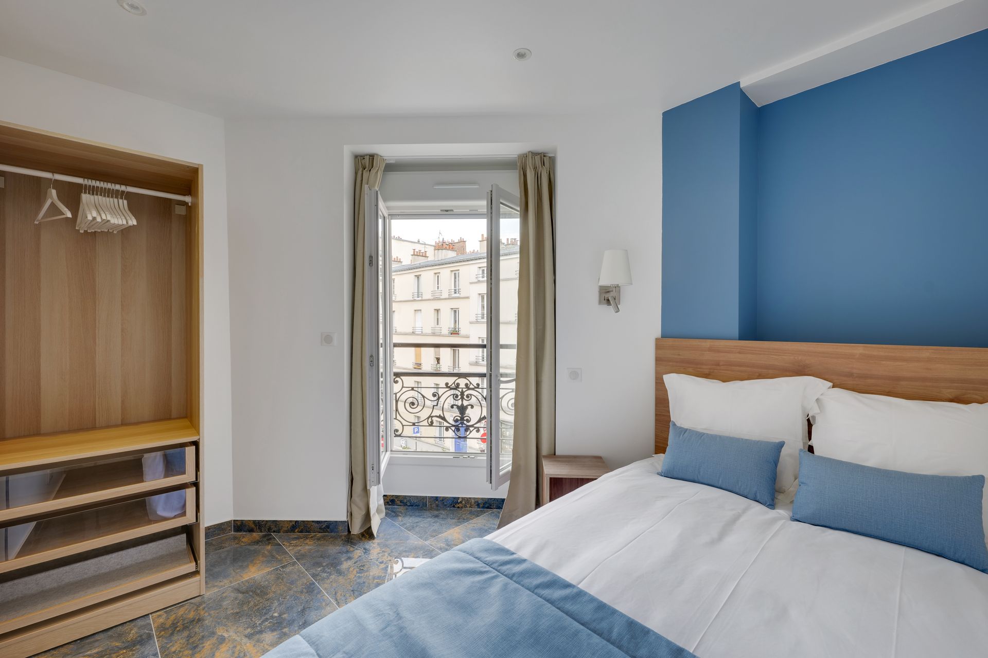Bedroom with a bed, closet, and window overlooking a city street. Blue and white color scheme.