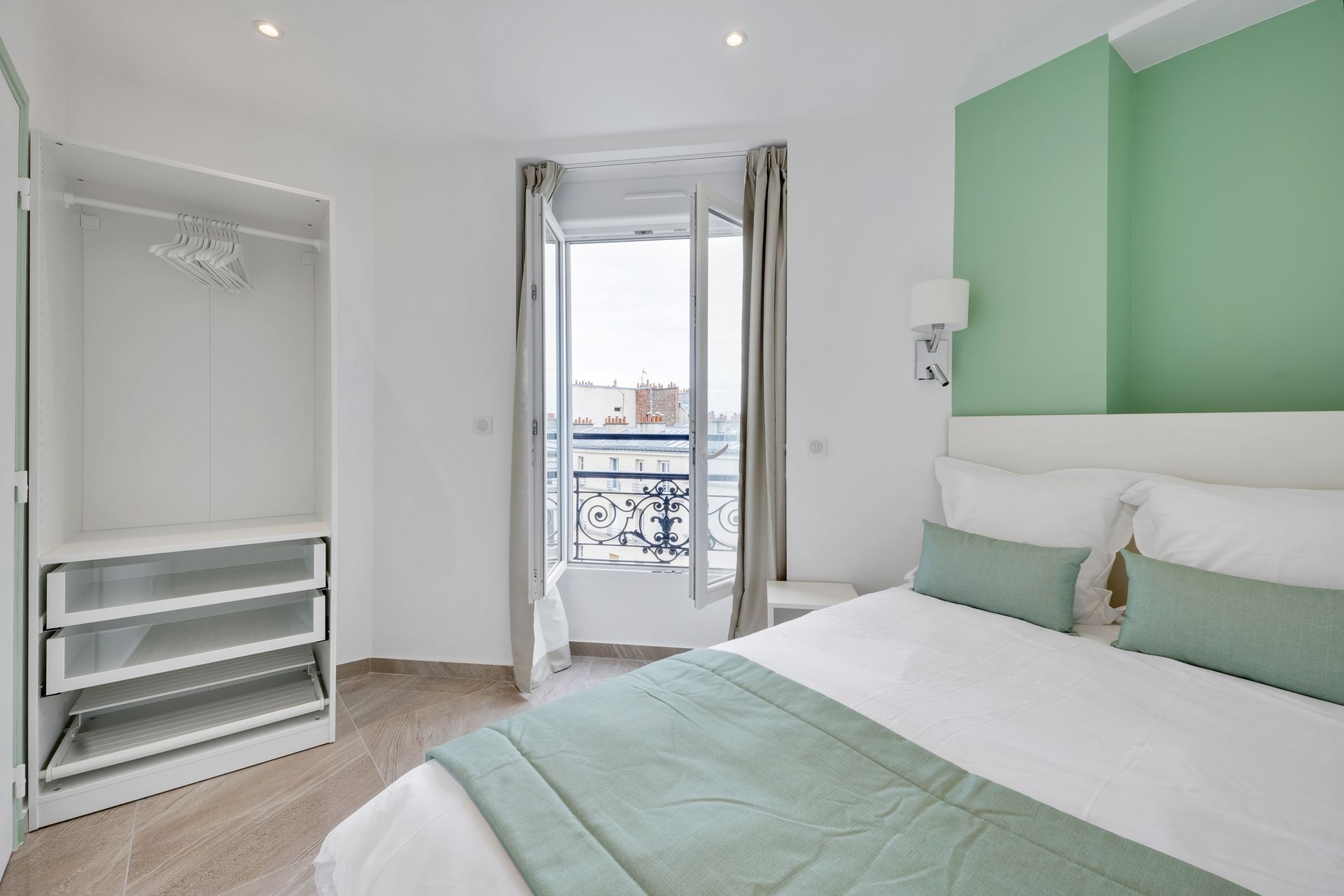 Bedroom with a bed, open window, closet, and mint-green accent wall.