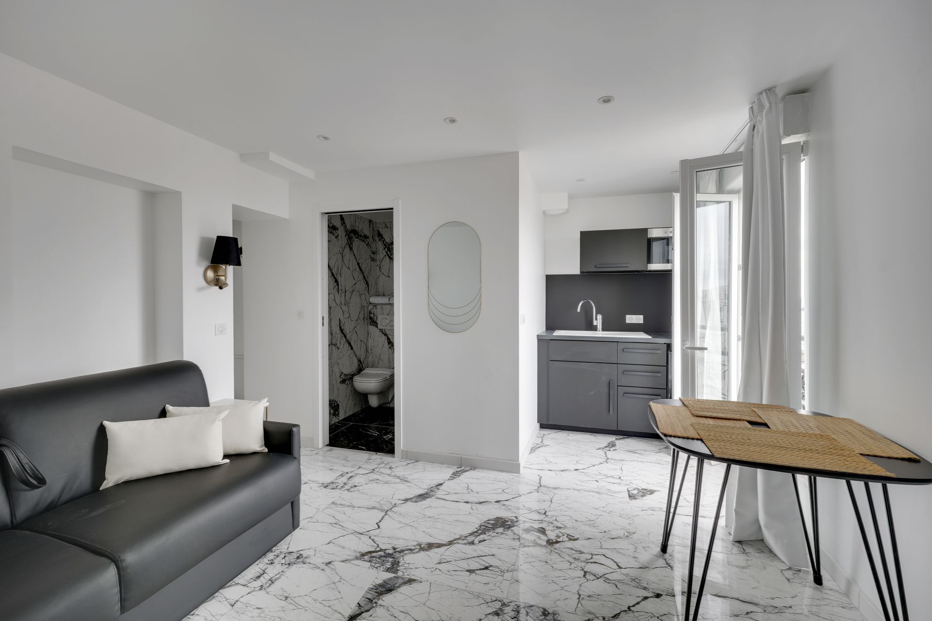 Small, modern apartment with black and white decor, featuring a living area, kitchen, and bathroom.