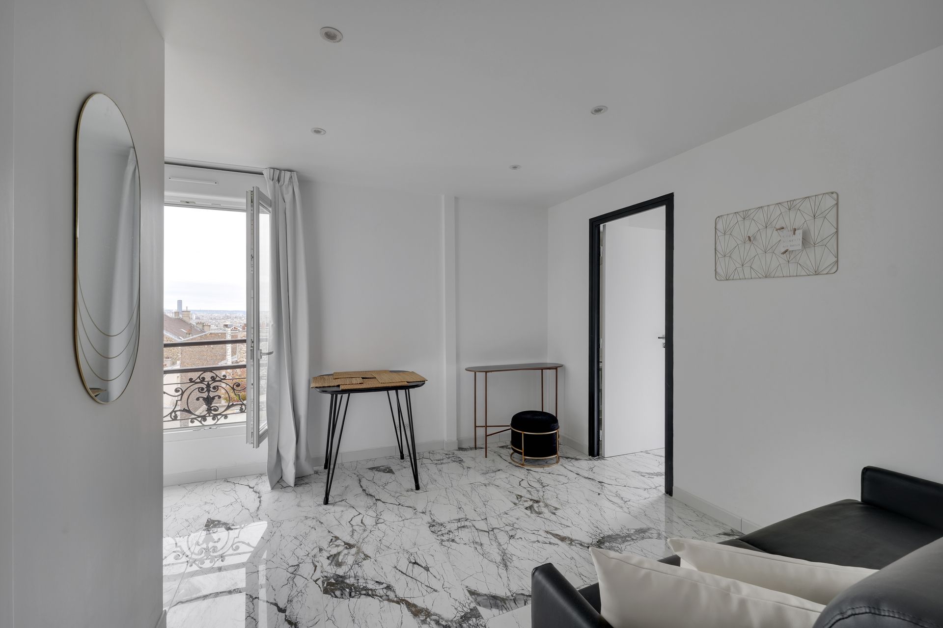 Bright white room with marble floors, a small table, open window, and black trim door.