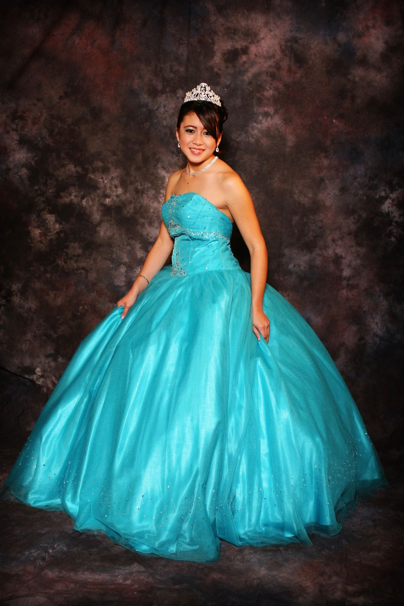 A woman in a blue ball gown and tiara is posing for a picture.