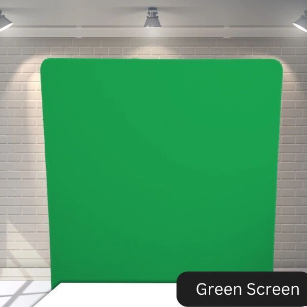 A green screen in front of a white brick wall