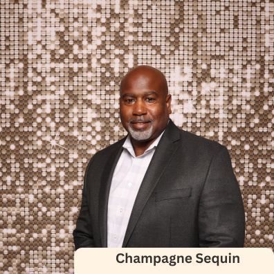 A man in a suit and white shirt is standing in front of a sequined wall.