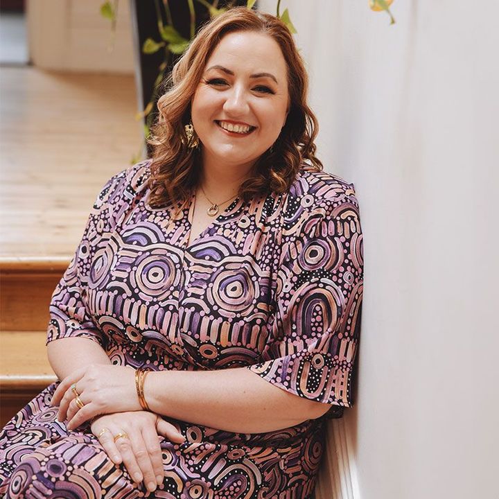 A woman in a purple dress is sitting on a set of stairs.