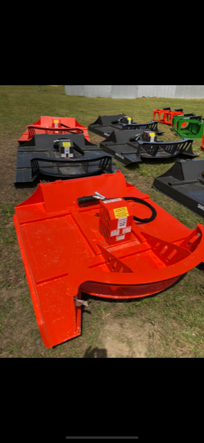 Several orange and black lawnmower decks sitting on grass.