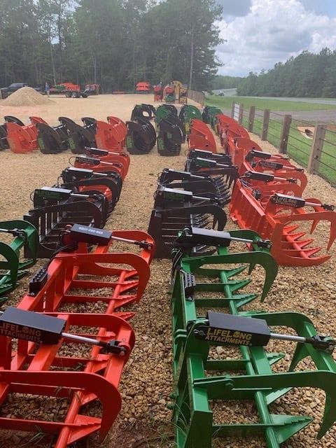 Rows of brightly colored grapple attachments for heavy machinery.
