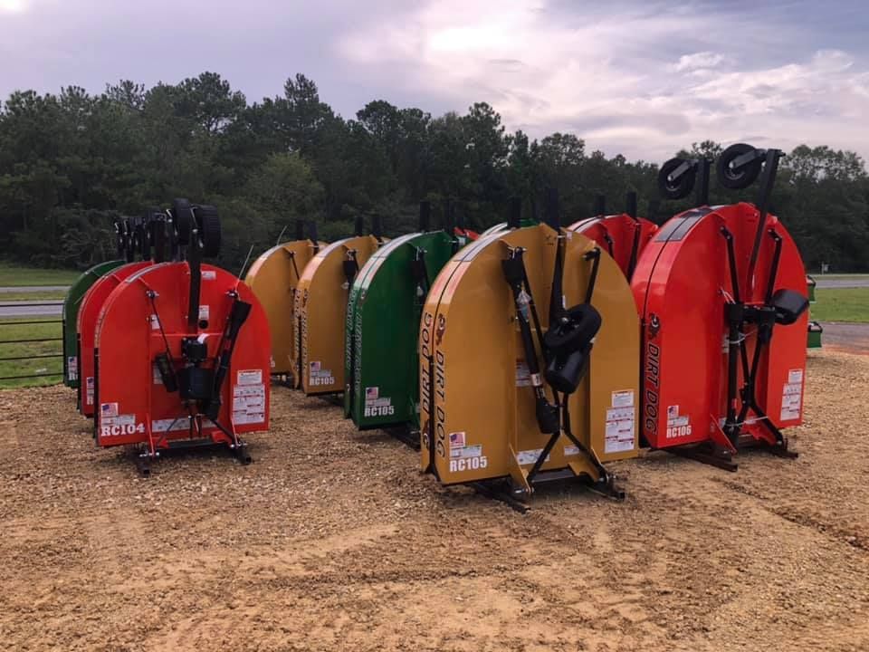 Several new tractor mowers parked in a gravel lot. Different colors: red, yellow, and green.