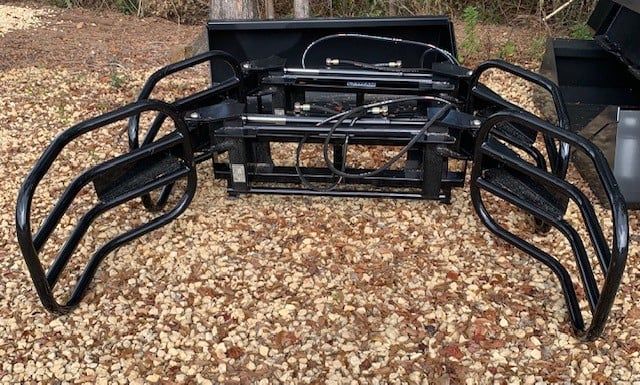 Black grapple attachment on a rocky surface, likely for a loader.