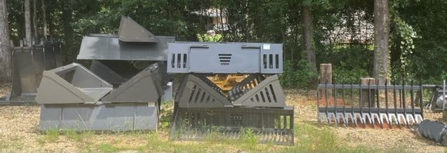 Various metal structures and equipment sit on grassy ground, trees in the background.