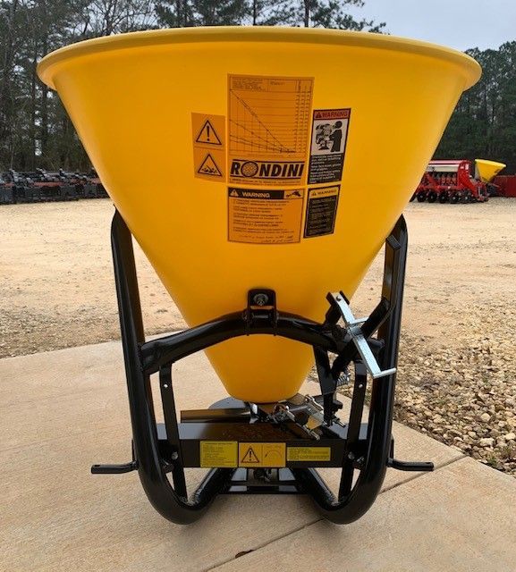 Yellow fertilizer spreader on a black metal frame, outdoors.