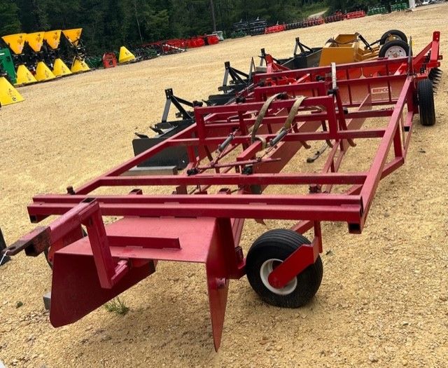 Red, rectangular land plane with wheels, used for leveling ground, sitting on gravel.