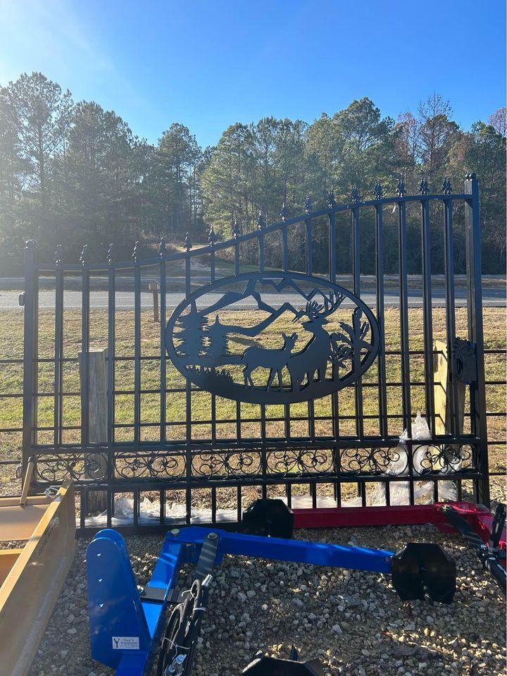 Black metal gate with decorative deer scene and blue farm equipment.