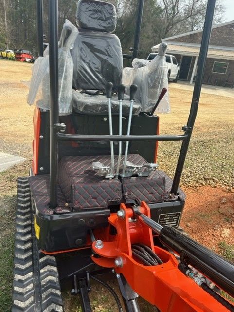 Orange and black mini excavator with tracks, controls, and seat.
