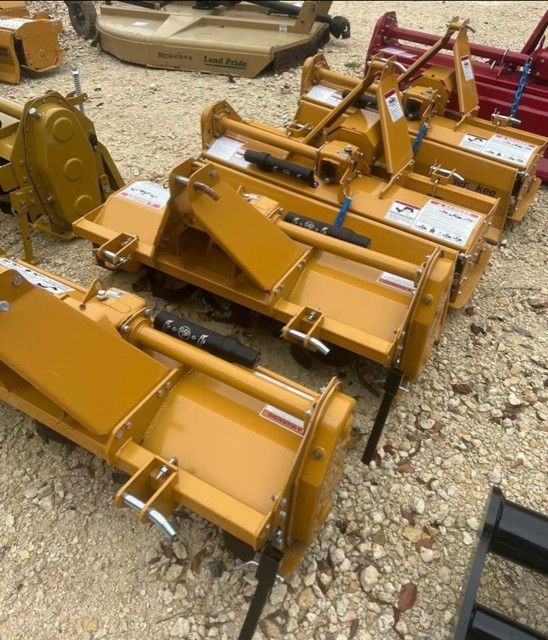Several new yellow rotary tillers sit outdoors.