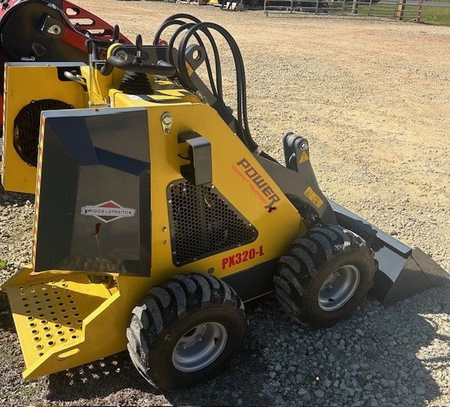 Yellow and gray Power X PK320-L mini skid steer with black tires parked on gravel.