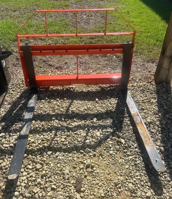 Orange forklift attachment on gravel with two silver forks.