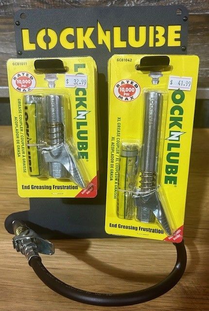 Two LockNLube grease fittings in packaging on a display stand; a black hose extends from the stand.