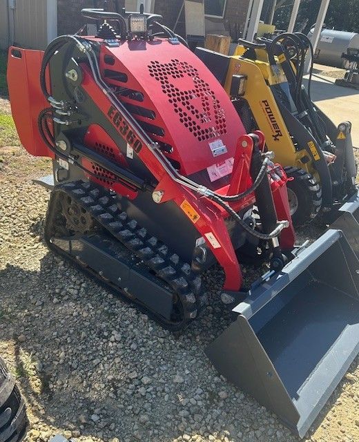 Red and black compact track loader with a bucket, in an outdoor setting.