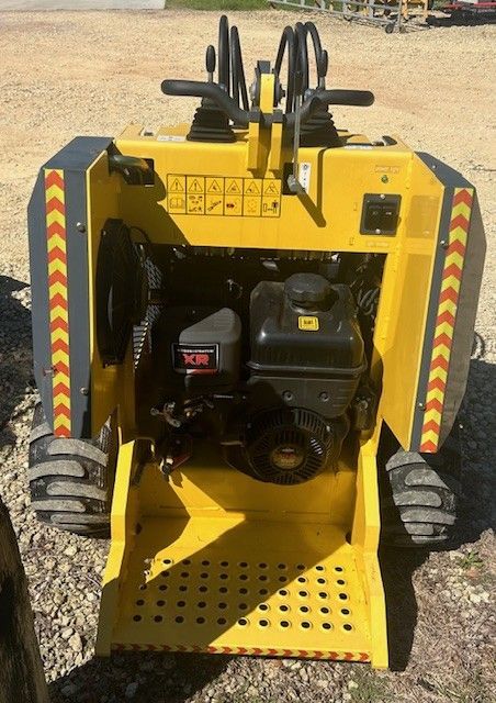 Yellow and gray mini skid steer, showing engine and operator controls.