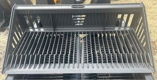 Black grapple bucket attachment with tines for a skid steer loader.