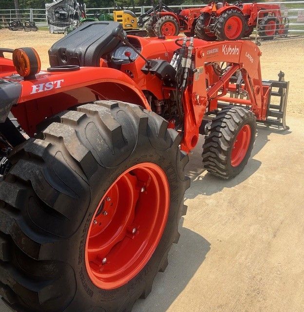 Orange Kubota tractor with front loader, parked on a paved surface.