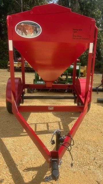 Red trailer with a large conical container; logo shows a cow; outdoors.