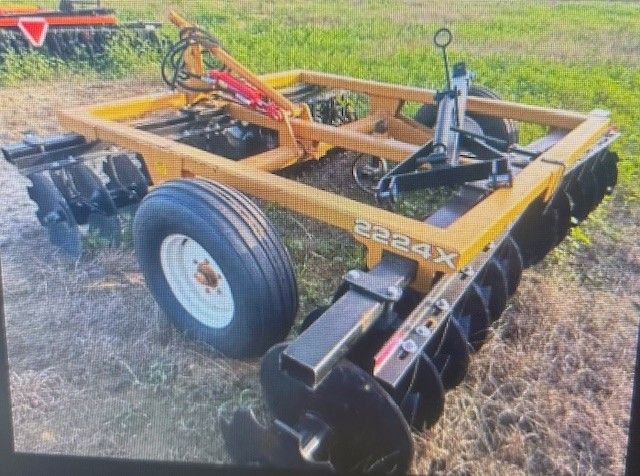 Yellow and black farm disc harrow with a large tire on a field.