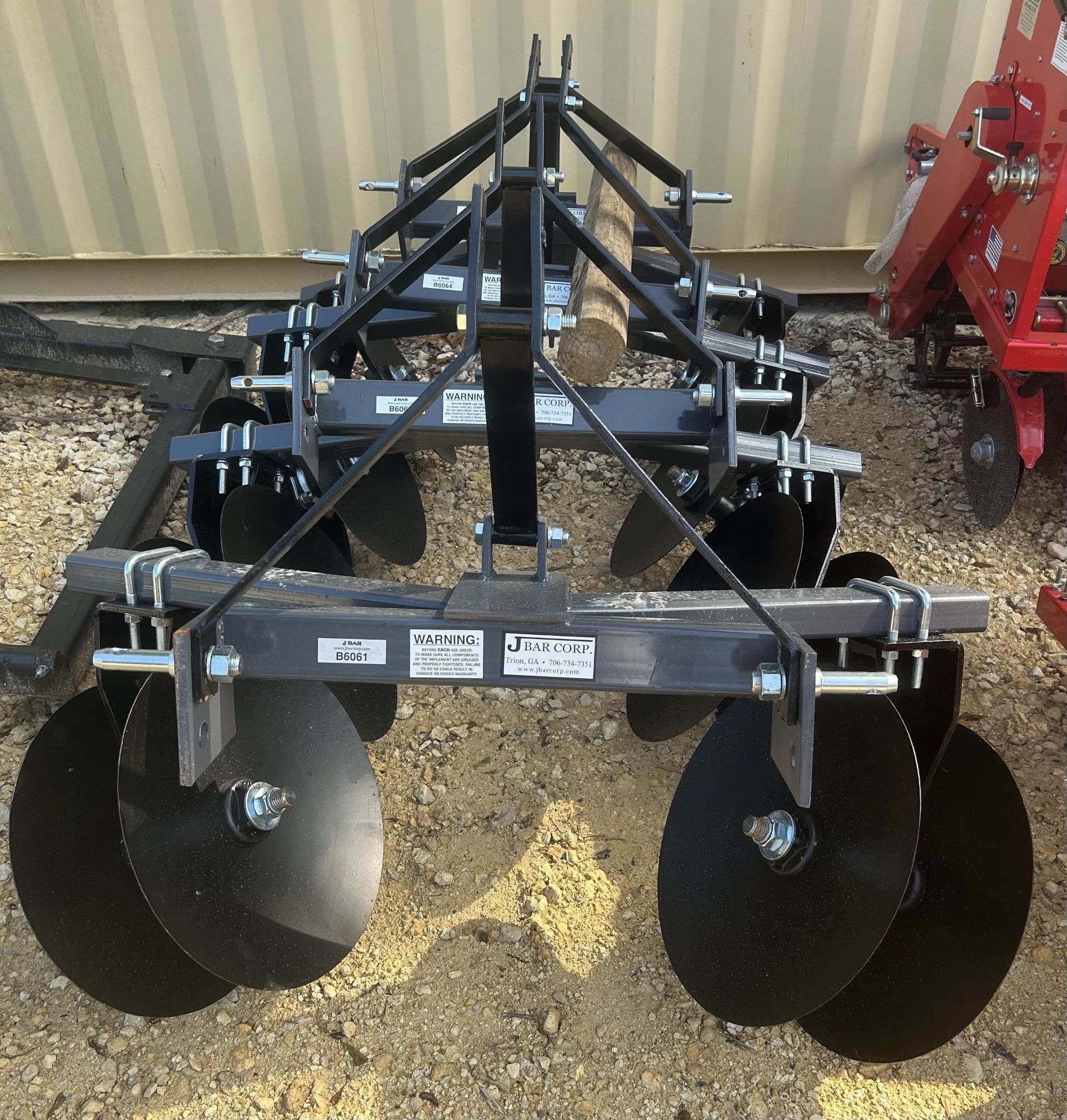 A black disc harrow used for agricultural plowing, with several curved blades and a metal frame.