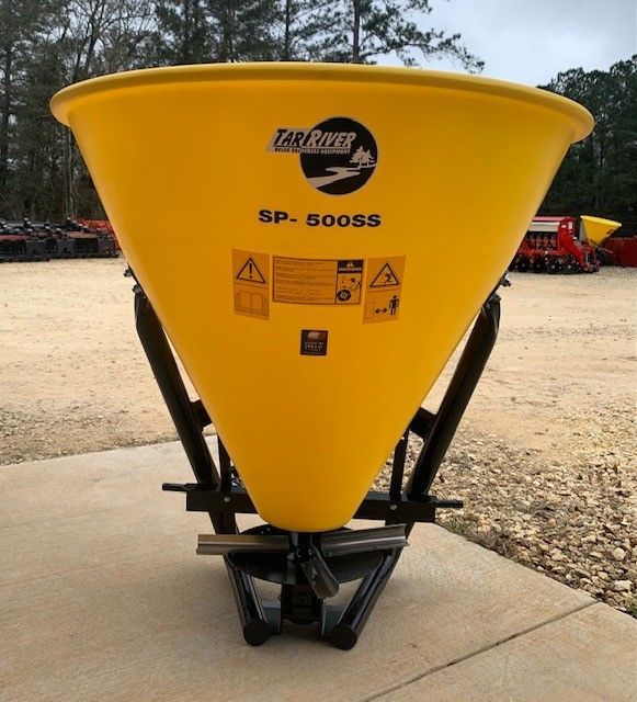 Yellow, cone-shaped fertilizer spreader, model SP-500SS, with black frame, outdoors.