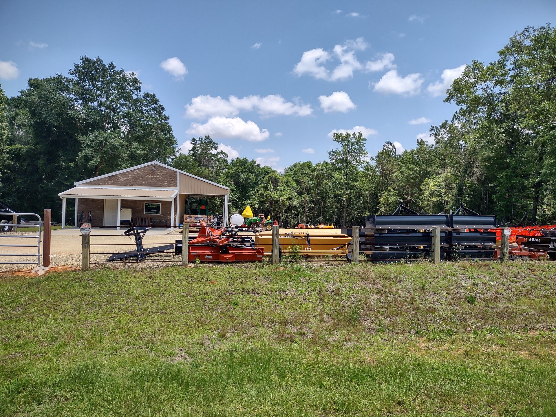 Equipment for sale in a yard in front of a small building under a blue sky.