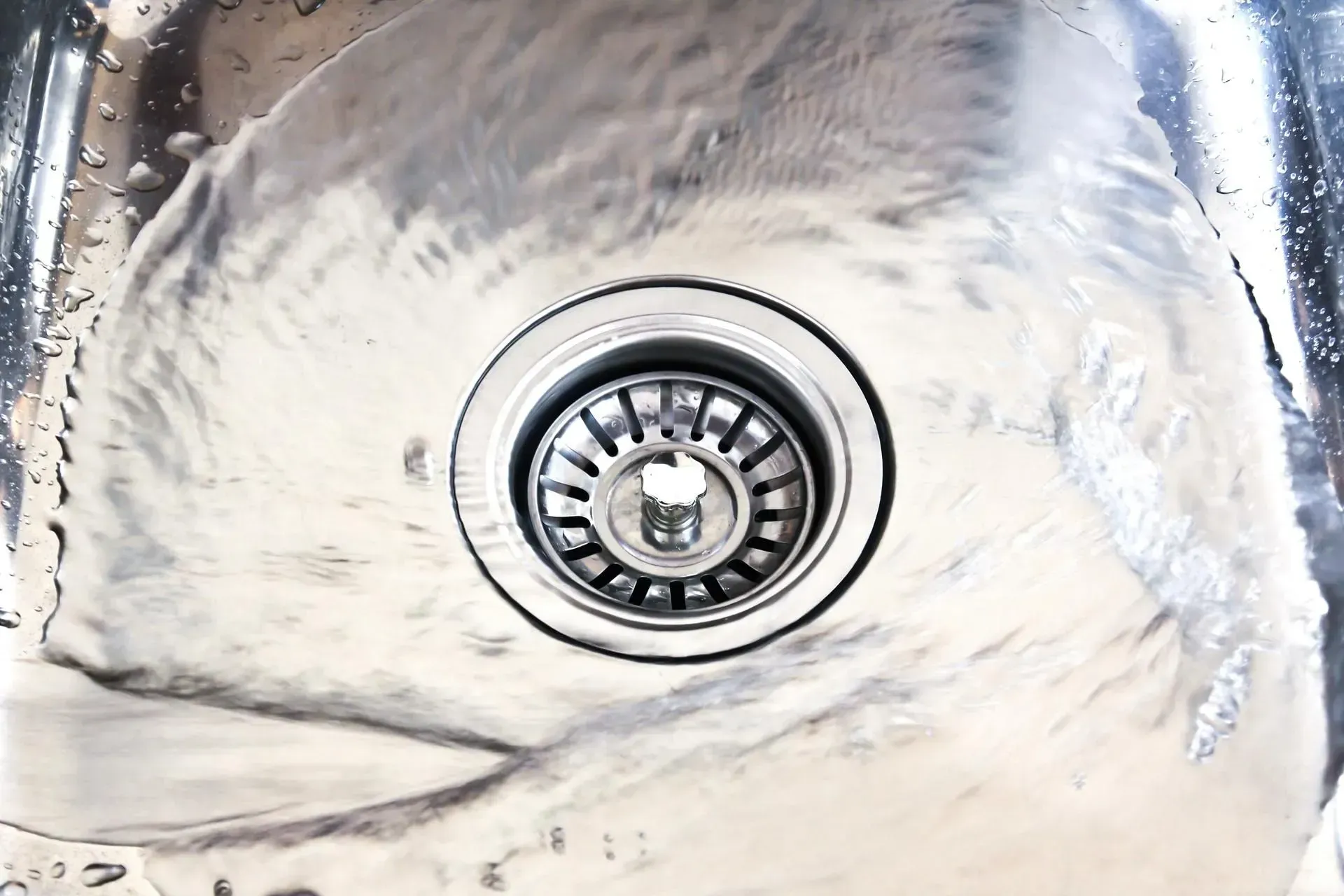A close up of a sink with water running down the drain A close up of a sink with water running down the drain