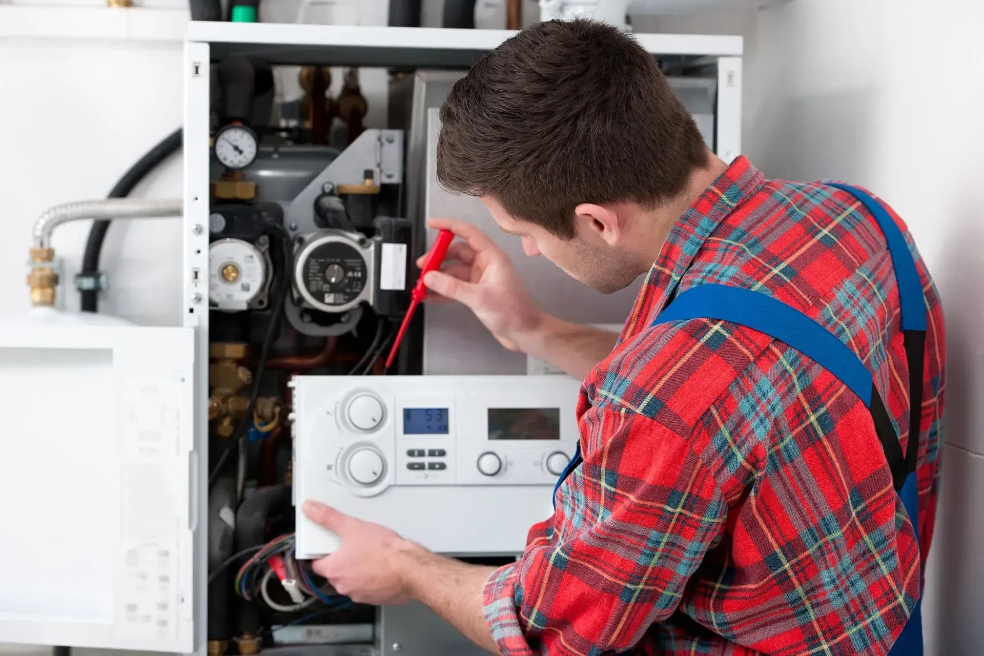 A man is fixing a boiler with a voltmeter. A man is fixing a boiler with a voltmeter.