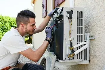 A man is fixing an air conditioner on the side of a building. A man is fixing an air conditioner on the side of a building.
