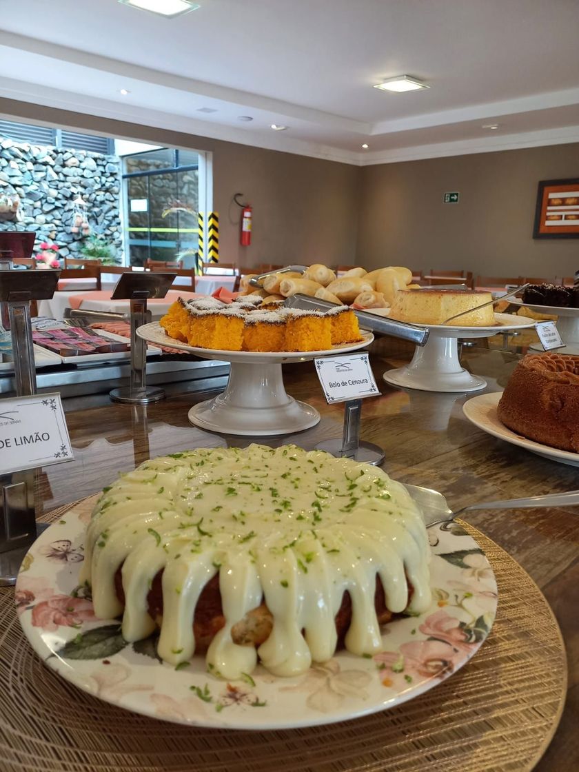 Buffet de café da manhã com itens de confeitaria, frutas e cereais.