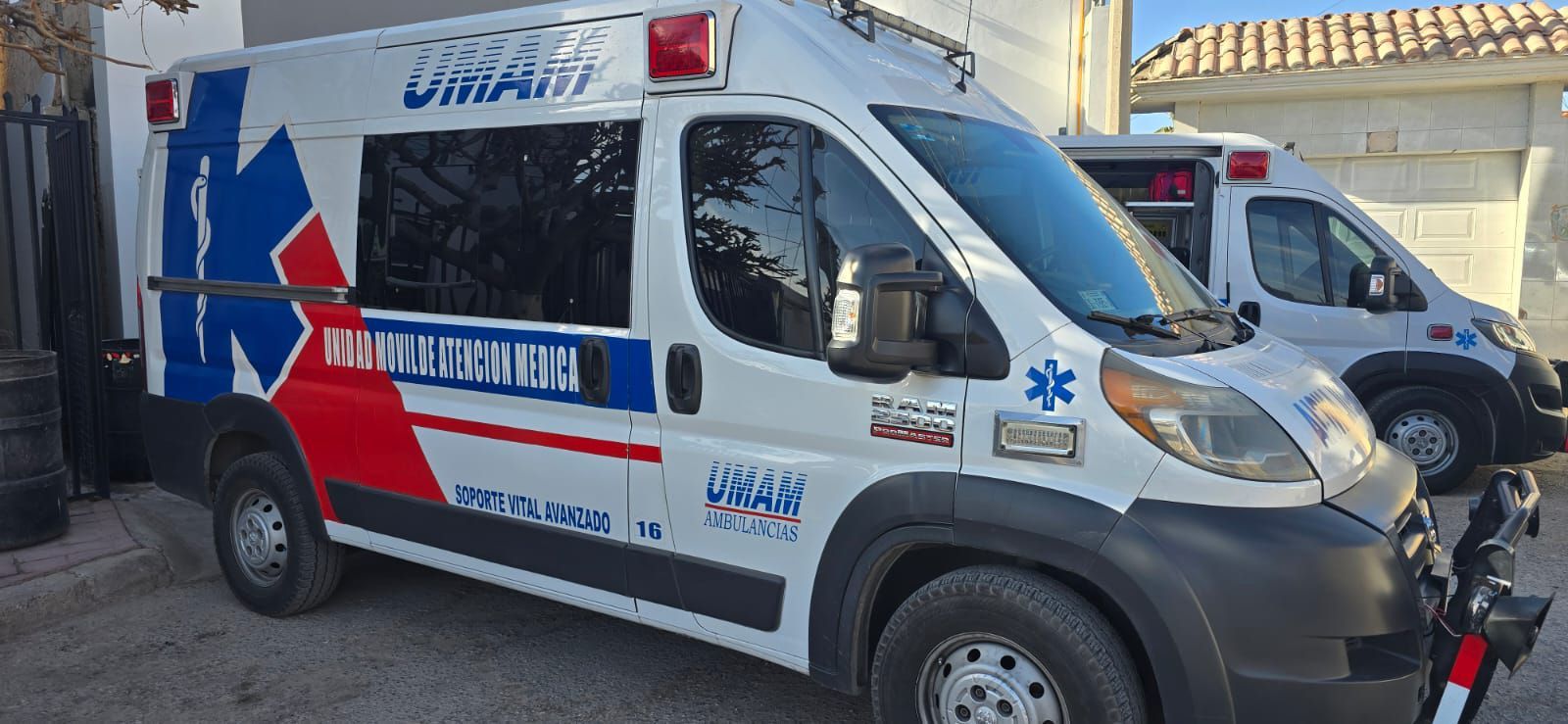 Dos ambulancias estacionadas al aire libre. Una ambulancia blanca tiene el logo de la estrella azul de la vida.
