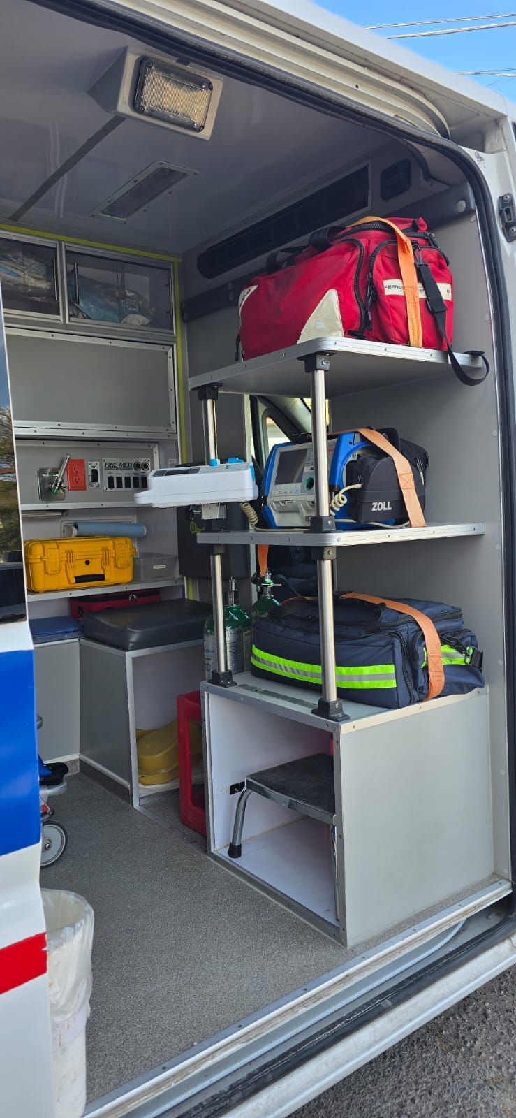 Interior de una ambulancia con estantes que contienen bolsas y equipos médicos.
